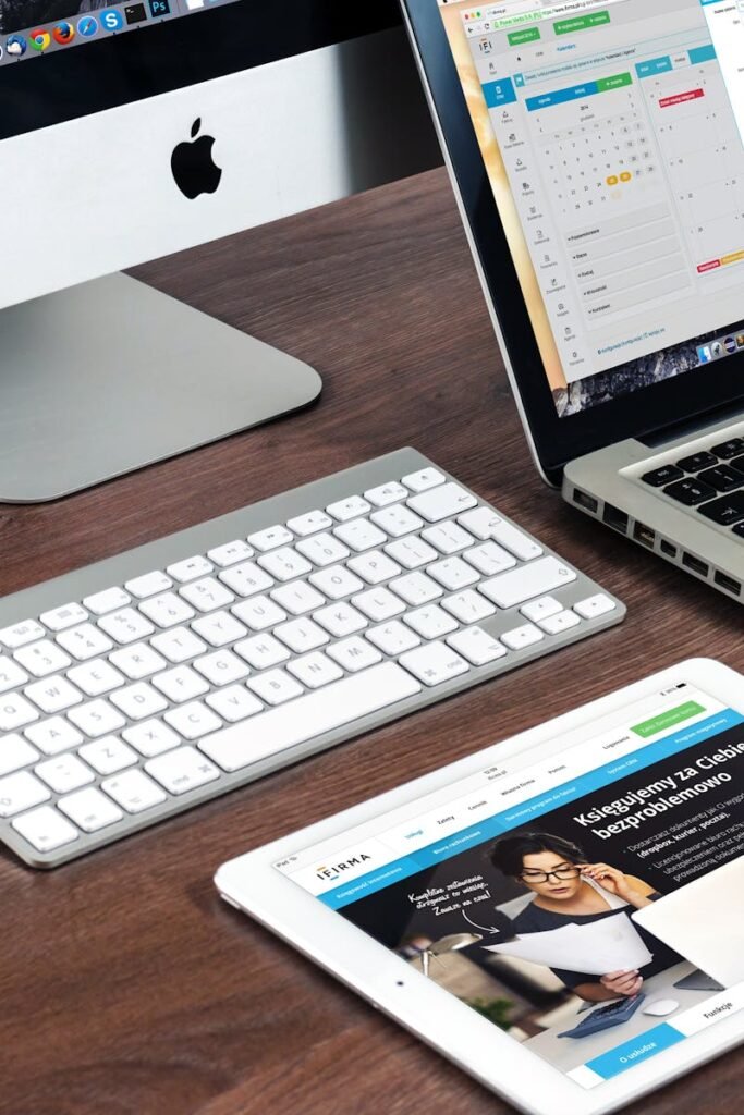 A sleek office desk setup featuring Apple devices: iMac, MacBook, and iPad.